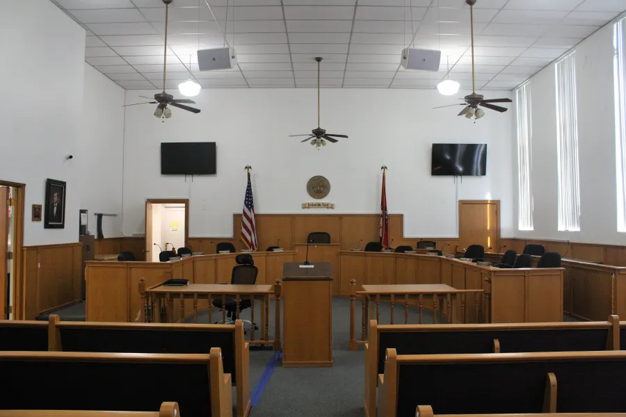 Bright courtroom with ceiling fans and wooden gallery benches