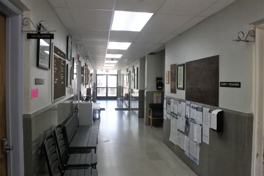 Courthouse hallway with benches and a bright window at the far end